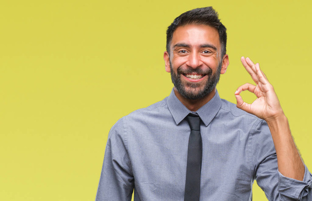 Взрослый латиноамериканец-бизнесмен на изолированном фоне улыбается позитивно, делая хорошо знак рукой и пальцами. Успешное выражение
. - Фото, изображение
