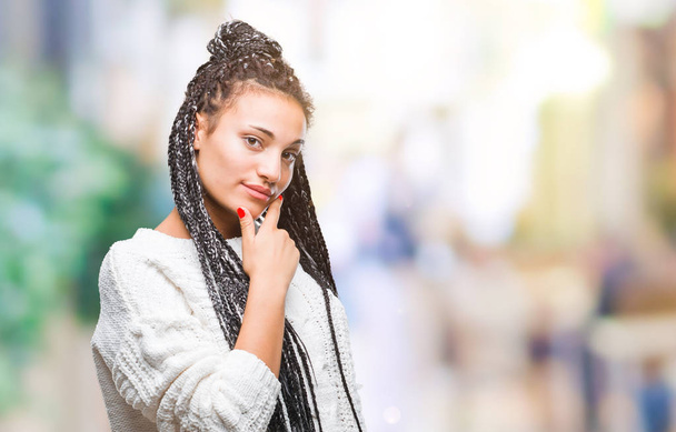 Молодая косичка африканская американка в свитере на изолированном фоне, уверенно смотрящая в камеру со скрещенными руками и поднятой на подбородок улыбкой. Мысли позитивно
. - Фото, изображение