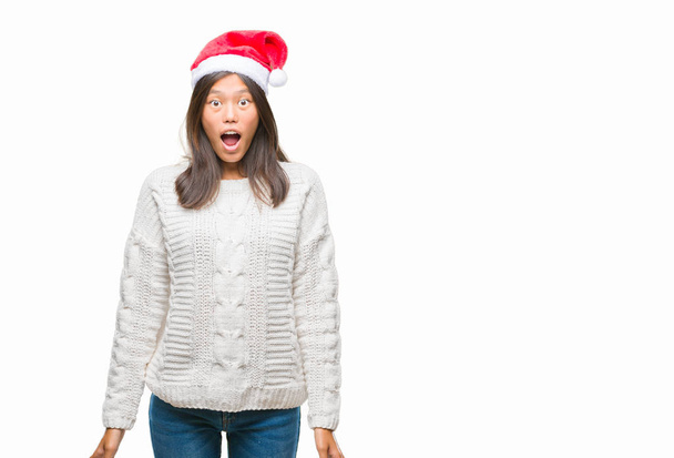 junge asiatische Frau mit Weihnachtsmütze über isoliertem Hintergrund ängstlich und schockiert mit überraschtem Ausdruck, Angst und aufgeregtem Gesicht. - Foto, Bild