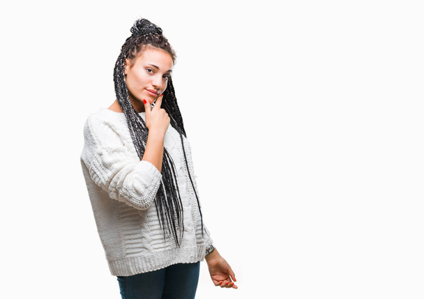 Joven chica afroamericana trenzada con suéter sobre fondo aislado que mira con confianza a la cámara con sonrisa con los brazos cruzados y la mano levantada en la barbilla. Pensando positivamente
. - Foto, imagen