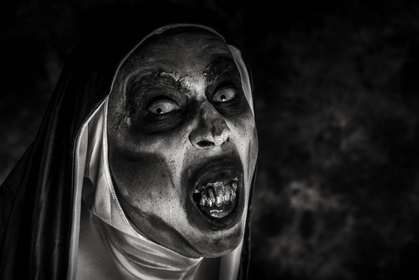 closeup of a scary evil nun, with frightening teeth, wearing a typical black and white habit, in black and white - Photo, Image