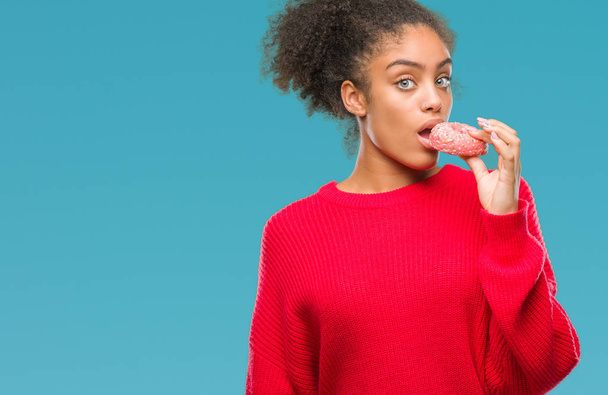 Mujer afroamericana joven comiendo donut sobre fondo aislado con una expresión de confianza en cara inteligente pensando en serio
 - Foto, Imagen
