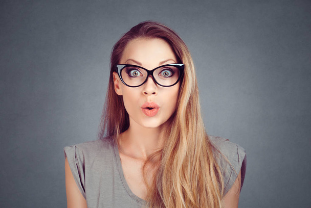 OMG, Wow. Close-up portrait of a beautiful excited stunned, surprised woman in eyeglasses isolated on gray grey studio wall Background. Positive face expression, human emotion body language - Foto, afbeelding