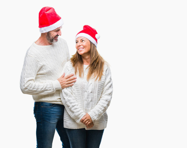 Испанская пара средних лет носит рождественскую шляпу на изолированном фоне со счастливой и прохладной улыбкой на лице. Счастливчик
. - Фото, изображение
