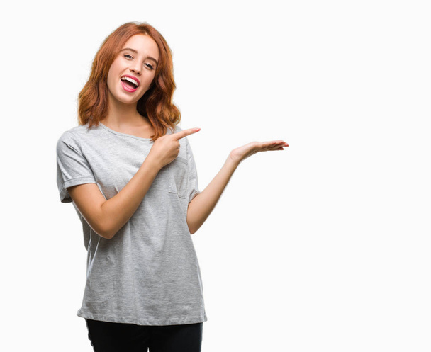 Young beautiful woman over isolated background amazed and smiling to the camera while presenting with hand and pointing with finger. - Foto, Imagen