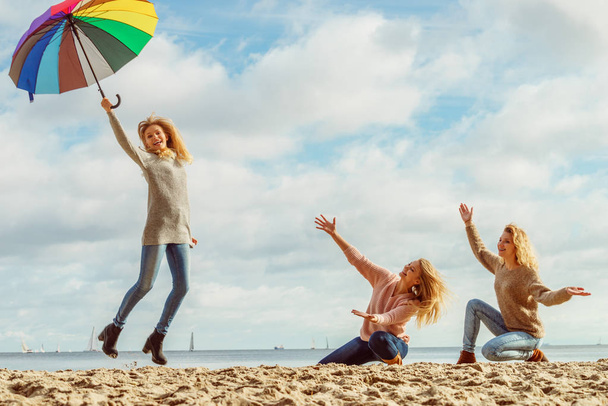 Three women full of joy having great time together. One woman holding colorful umbrella. - Photo, Image
