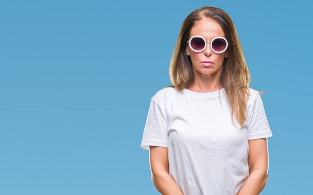Испанская женщина средних лет в модных солнцезащитных очках на изолированном фоне с серьезным выражением лица. Простой и естественный взгляд на камеру
. - Фото, изображение