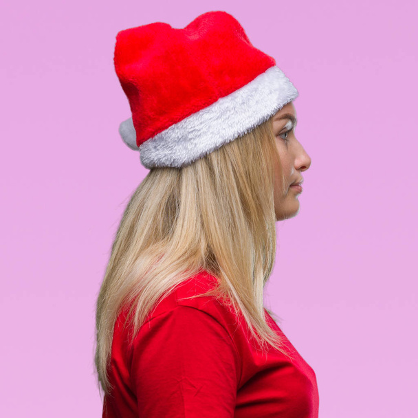 Young caucasian woman wearing christmas hat over isolated background looking to side, relax profile pose with natural face with confident smile. - Foto, Imagem