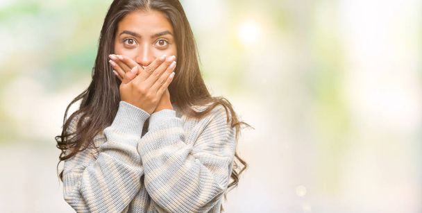 Young beautiful arab woman wearing winter sweater over isolated background shocked covering mouth with hands for mistake. Secret concept. - Photo, image