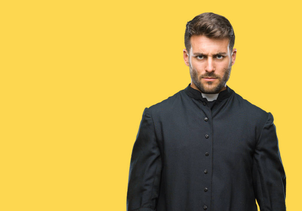 Young catholic christian priest man over isolated background skeptic and nervous, frowning upset because of problem. Negative person. - Photo, Image