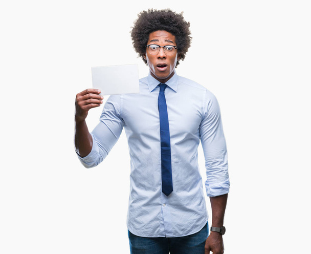 Afro amerikai ember tartja üres kártya, elszigetelt háttérhez képest félek a sokk egy meglepetés arc, fél és izgatott félelem kifejezés - Fotó, kép