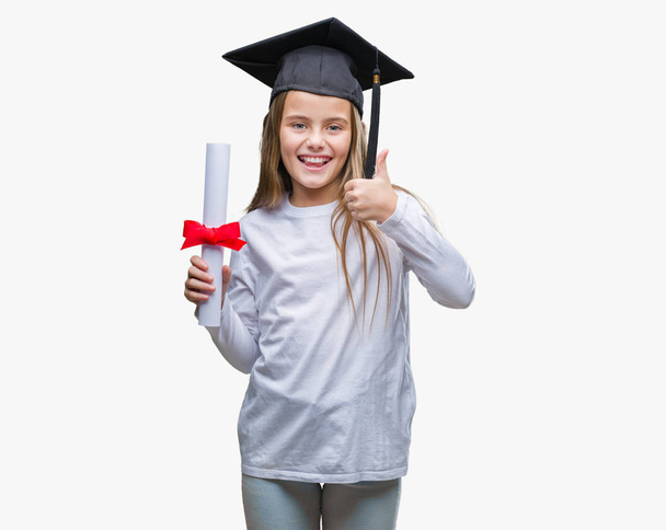 Молода красива дівчина в шапці випускника, що тримає ступінь над ізольованим тлом щаслива з великою посмішкою робить знак ок, великий палець пальцями, відмінний знак
 - Фото, зображення