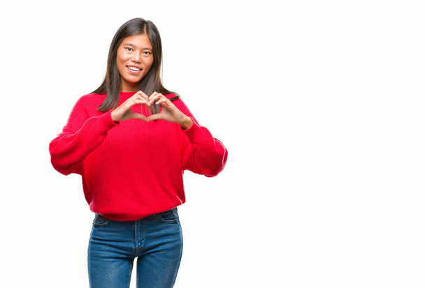 Young asian woman wearing winter sweater over isolated background smiling in love showing heart symbol and shape with hands. Romantic concept. - Foto, immagini