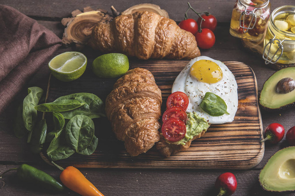 Croissant mit Guacamole-Avocado, Spiegelei und Tomaten, Spinatblättern. vegetarisches Gericht - Foto, Bild
