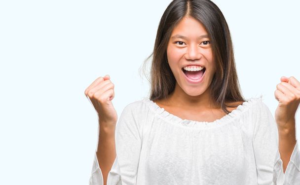 Genç Asyalı kadın kutluyor izole arka plan üzerinde şaşırttı ve başarı için kaldırdı kollarını açarak hayret ve gözleri açık. Kazanan kavramı. - Fotoğraf, Görsel