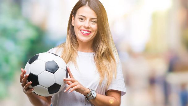 Young beautiful woman holding soccer ball over isolated background with a happy face standing and smiling with a confident smile showing teeth - Фото, изображение