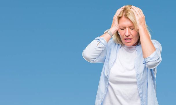 Middle age blonde woman over isolated background suffering from headache desperate and stressed because pain and migraine. Hands on head. - Foto, afbeelding