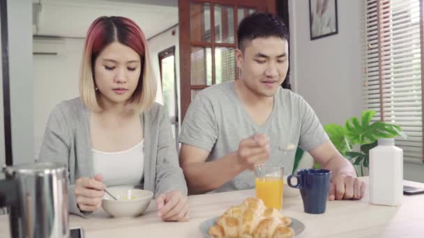 Feliz pareja asiática dulce desayunando, cereales con leche, pan y zumo de naranja después de despertarse por la mañana. Marido y su esposa comiendo juntos
. - Imágenes, Vídeo