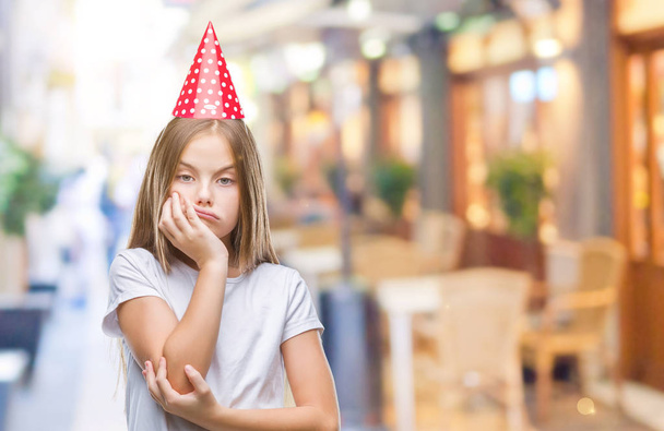Молодая красивая девушка в праздничной шапке на изолированном фоне думает усталый и скучно с депрессией проблемы со скрещенными руками
. - Фото, изображение