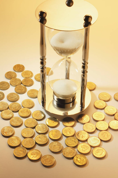 Hourglass and Coins in Warm Cast - Valokuva, kuva