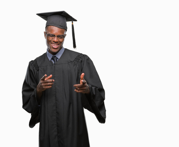 junger afrikanisch-amerikanischer Hochschulabsolvent vor isoliertem Hintergrund, der mit fröhlichem und lustigem Gesicht mit dem Finger in die Kamera zeigt. gute Energie und Stimmung. - Foto, Bild