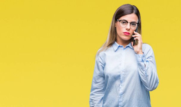 Молодая красивая деловая женщина говорит с помощью смартфона на изолированном фоне с уверенным выражением на умном лице, думая серьезно
 - Фото, изображение