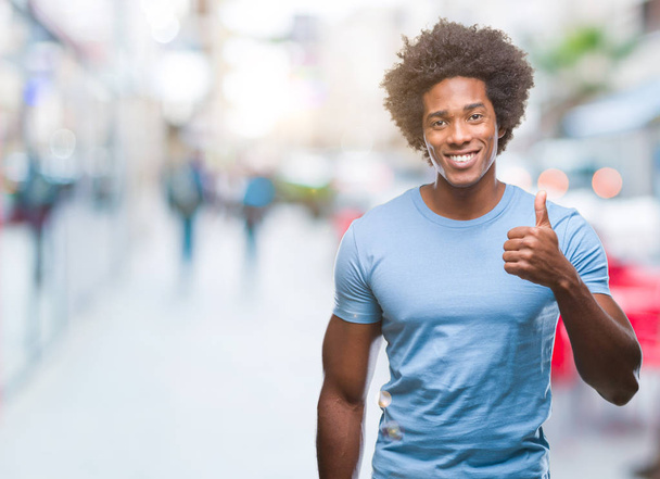 Afro american man over isolated background doing happy thumbs up gesture with hand. Approving expression looking at the camera with showing success. - Zdjęcie, obraz
