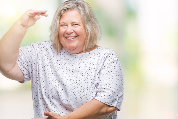 Senior plus size caucasian woman over isolated background gesturing with hands showing big and large size sign, measure symbol. Smiling looking at the camera. Measuring concept. - Fotoğraf, Görsel