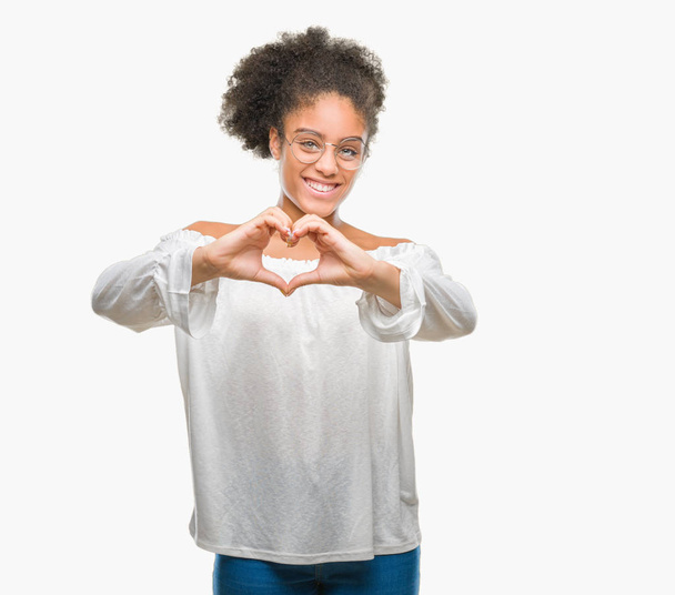 Young afro american woman wearing glasses over isolated background smiling in love showing heart symbol and shape with hands. Romantic concept. - Фото, зображення