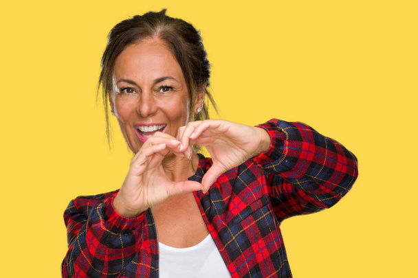 Middle age adult woman wearing casual jacket over isolated background smiling in love showing heart symbol and shape with hands. Romantic concept. - Photo, Image
