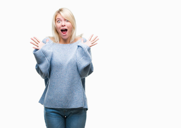 Joven mujer rubia hermosa vistiendo suéter de invierno sobre fondo aislado celebrando loco y sorprendido por el éxito con los brazos levantados y los ojos abiertos gritando emocionados. Concepto ganador
 - Foto, imagen