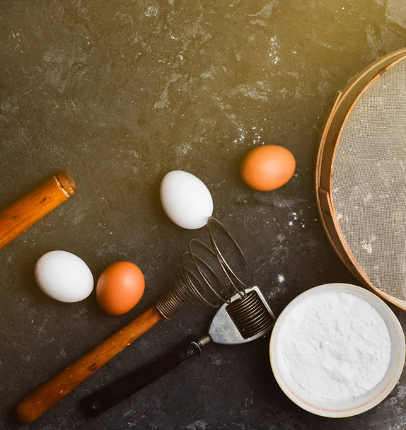  Συστατικά για τα ζυμαρικά. Η διαδικασία του μαγειρέματος. Αυγά, αλεύρι, εργαλεία κουζίνας σε έναν μαύρο πίνακα σκυροδέματος. Εργαλεία για το μαγείρεμα. Ιταλική κουζίνα. Το Top view. Επίπεδη θέσει.  - Φωτογραφία, εικόνα