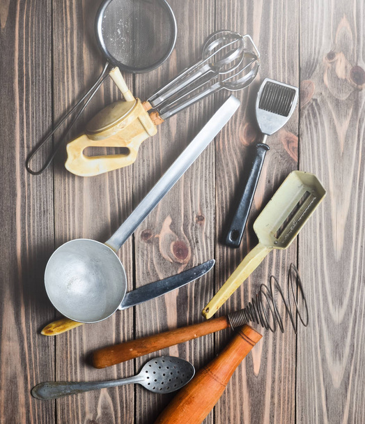 A set of old kitchen tools and cutlery on a wooden table. Vintage cooking in the kitchen. Top view. - Photo, image