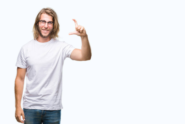 Young handsome man with long hair wearing glasses over isolated background smiling and confident gesturing with hand doing size sign with fingers while looking and the camera. Measure concept. - Foto, Imagem