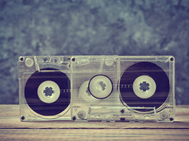 灰色のコンクリートの壁に木製の棚のオーディオ ・ カセット テープのクローズ アップ。音楽を聴くためのレトロな技術. - 写真・画像