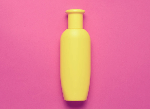 Żółta butelka szamponu na różowym tle. Trend minimalizmu. Widok z góry. Produkty dla prysznic. Miejsca na tekst. - Zdjęcie, obraz