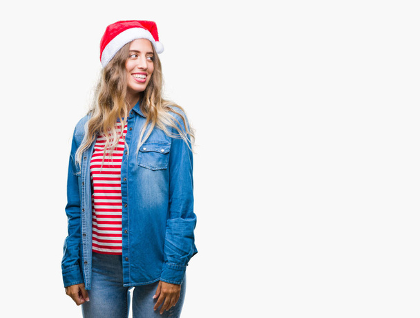 Kaunis nuori blondi nainen yllään joulu hattu yli eristetty tausta katselee pois puolelta hymyillen kasvot, luonnollinen ilme. Nauraen itsevarmana
. - Valokuva, kuva