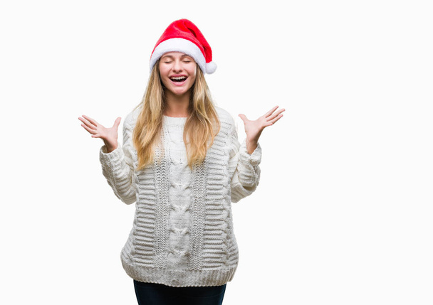 Fiatal gyönyörű szőke nő, fárasztó karácsonyi kalap alatt elszigetelt háttér ünnepli, őrült és őrült siker karokkal emelt és zárt szemek sikoltozik izgatott. Győztes koncepció - Fotó, kép