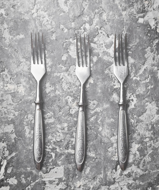 Three antique forks on a gray concrete table. Top view. - Fotó, kép