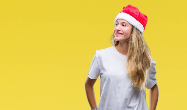 若い美しいブロンドの女性の上クリスマスの帽子をかぶっては、背景が笑顔で側に自然な表現の顔に離れて見て分離。自信を持って笑ってください。. - 写真・画像