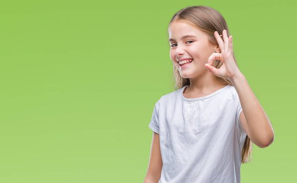 Young beautiful girl over isolated background smiling positive doing ok sign with hand and fingers. Successful expression. - Photo, Image