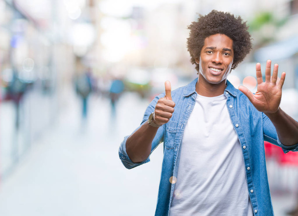 Афро-американец на изолированном фоне показывает и показывает пальцами номер шесть, улыбаясь уверенно и счастливо
. - Фото, изображение