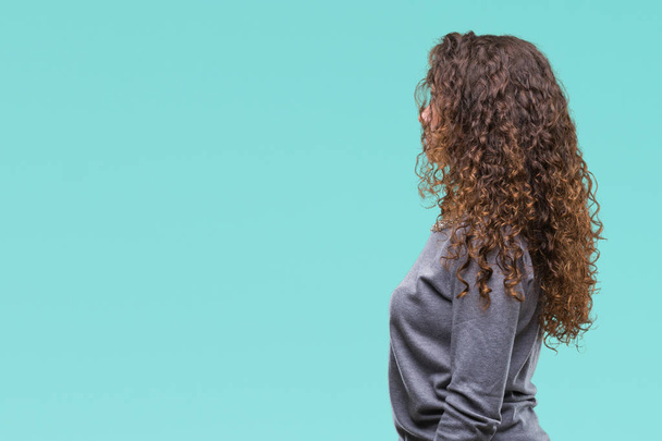 schöne brünette lockige Haare junges Mädchen trägt einen Pullover über isoliertem Hintergrund Blick zur Seite, entspannen Profil-Pose mit natürlichem Gesicht mit selbstbewusstem Lächeln. - Foto, Bild