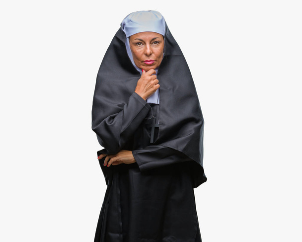 A középkorú vezető keresztény katolikus apáca nő keresi benne, a kamera mosollyal karokkal és kezével az álla emelt elszigetelt háttérhez képest. Pozitív gondolkodás. - Fotó, kép