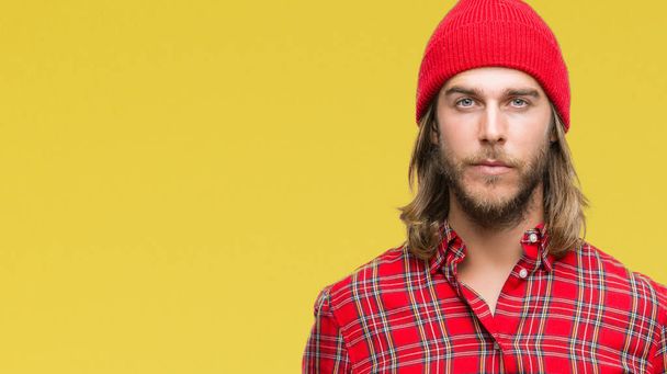 Young handsome man with long hair wearing red cap over isolated background with serious expression on face. Simple and natural looking at the camera. - Fotografie, Obrázek
