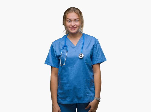 Young caucasian doctor woman wearing surgeon uniform over isolated background with a happy and cool smile on face. Lucky person. - Foto, Imagen
