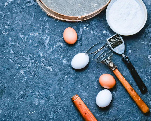 Ingrediënten voor pasta. Het kookproces. Eieren, meel, keukengerei op een zwarte betonnen tafel. Hulpmiddelen voor het koken. Italiaanse keuken. Bovenaanzicht. Plat leggen. - Foto, afbeelding