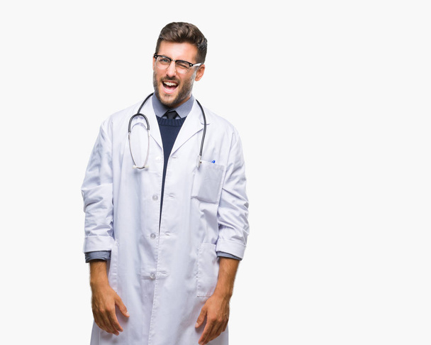 Young handsome doctor man over isolated background winking looking at the camera with sexy expression, cheerful and happy face. - 写真・画像