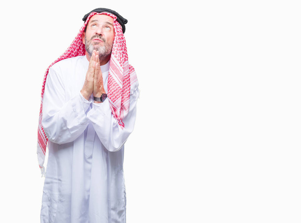 シニアのアラブ人は、懇願するような非常に感情的なおよび心配の顔希望表現とともに手で祈って分離の背景にクーフィーヤを着用します。赦しを乞います。宗教概念. - 写真・画像