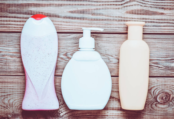 Flaschen mit Produkten für das Badezimmer. Duschgel, Flüssigseife, Shampoo auf einem Holztisch. Ansicht von oben. - Foto, Bild